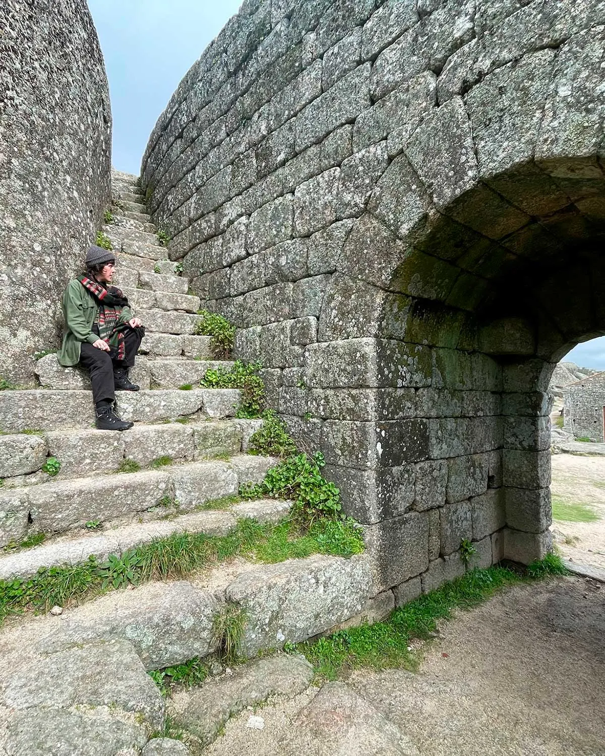 Jesi sitting on stone steps beside an old stone archway in Portugal